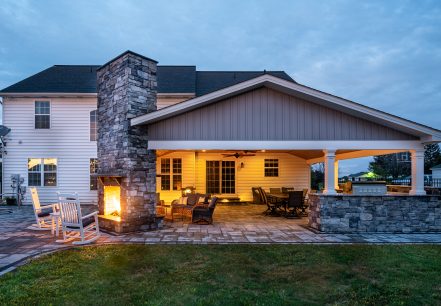 newly built backyard porch with stone fireplace and multiple furniture sets