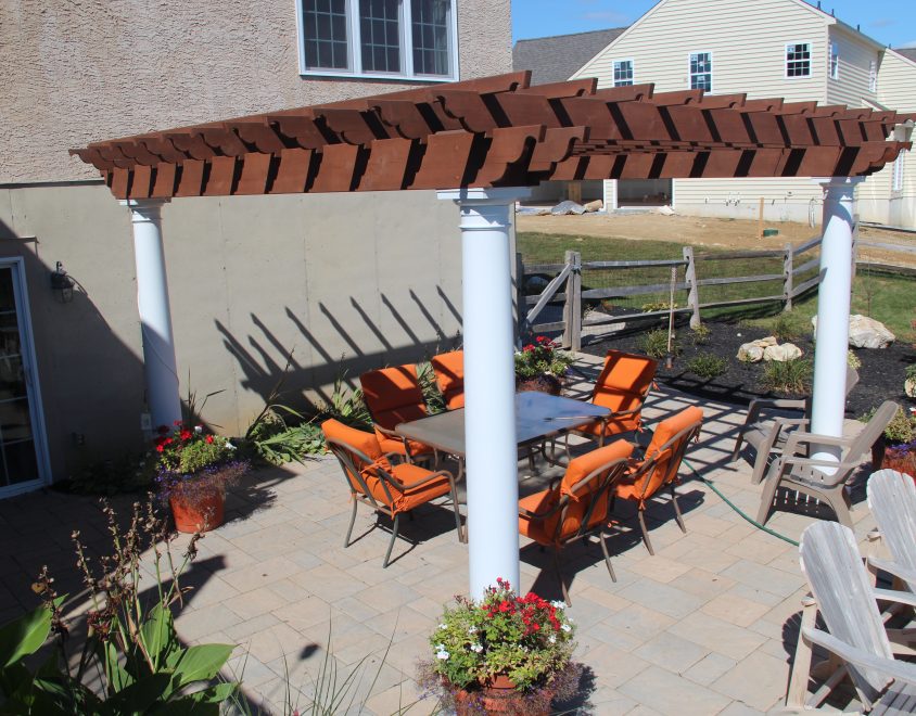 patio pergola and dining set surrounded by potted plants