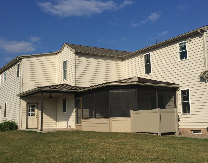 newly built sun room addition on home with tan vinyl siding