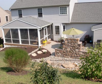 sun room addition on home with outdoor dining area and several bushes